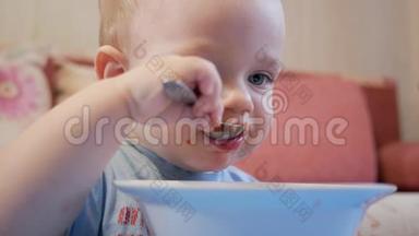<strong>一个</strong>2岁有魅力的男孩自己在吃红汤。 <strong>勺子</strong>和手流动的液体。 健康饮食的概念